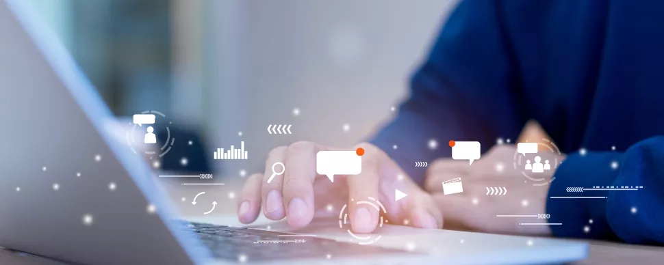 Person typing on a laptop with digital icons floating above the keyboard.