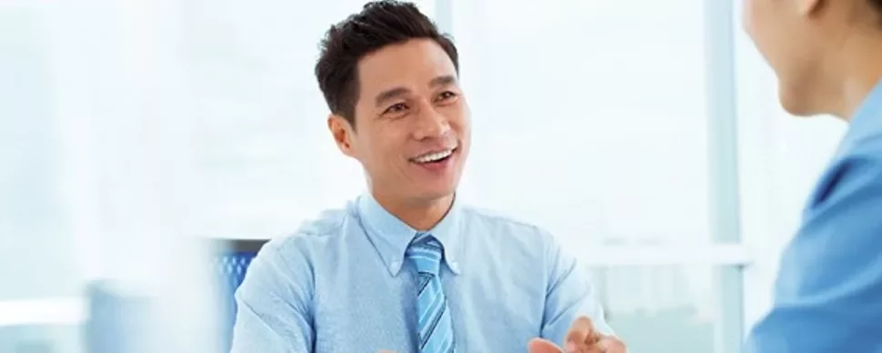 Man in a blue shirt smiling during a meeting.