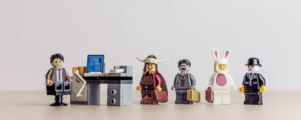 Lego minifigures in costume line up in an office setting.