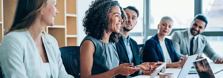 A diverse group of people smiling and talking in a meeting room.