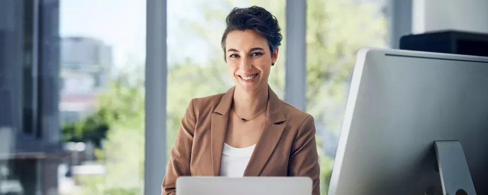 Smiling woman at her desk with a computer in a modern office.