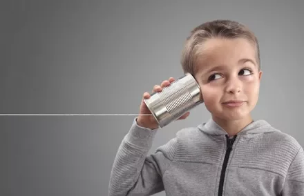 Child listens with a tin can telephone, string pulled taut.