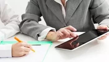 Two business people working on documents and using a tablet.