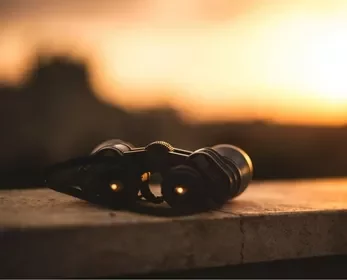Binoculars on a ledge at sunset with a blurred background.
