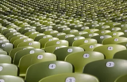 Rows of empty green stadium seats with numbered labels.