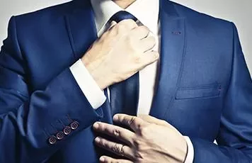 Person in a blue suit adjusting a tie.