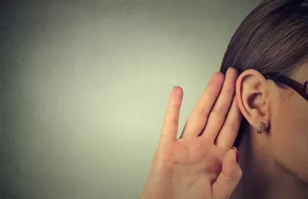 Person cupping hand to ear, listening intently.