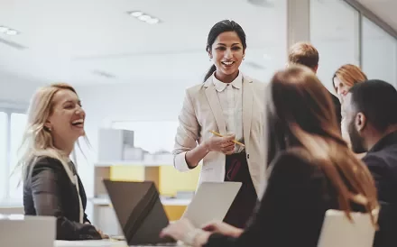 Group of professionals in a meeting, smiling and interacting.