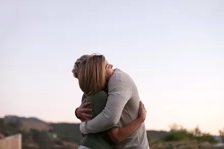 Two people embracing outdoors during sunset.