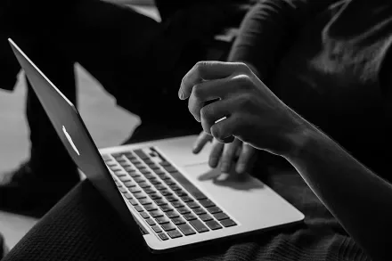 Person typing on a laptop, monochrome setting.