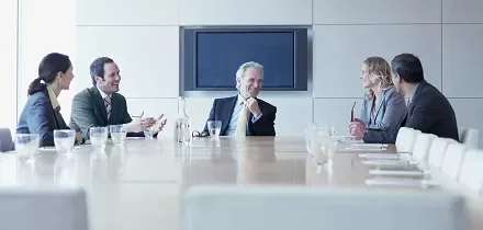 Five business people in a conference room having a discussion.