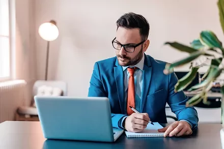 Man in blue suit working on laptop at a desk