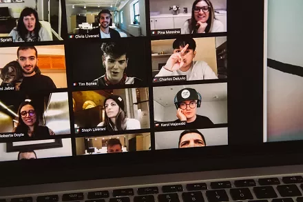 A virtual meeting with multiple participants displayed in a grid on a laptop screen.